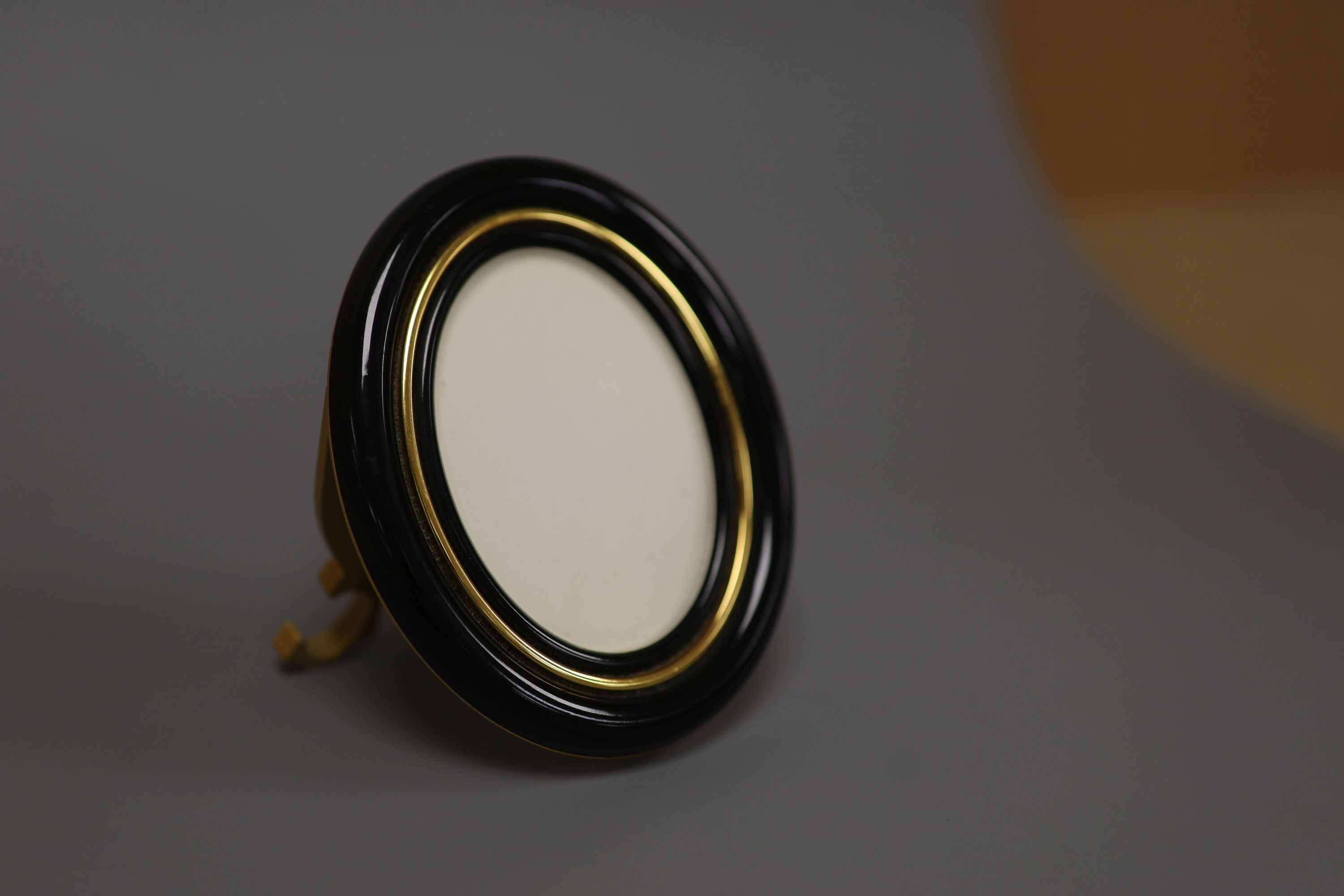 A Must de Cartier black lacquered and gilt oval easel photograph frame, length 9cm